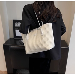 White woven tote bag with leather straps shown in a minimalist interior setting