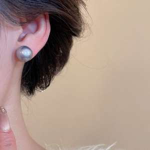Detail of a high-luster 12mm grey round pearl stud earring worn on model's ear