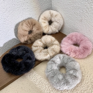 Close-up of plush velvet hair scrunchies in gray, black, pink, and beige earth tones