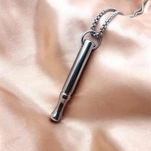 Close-up of a polished stainless steel meditation breathing necklace on satin background
