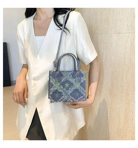 Blue denim crossbody bag with green star pattern and frayed fringe shown on model