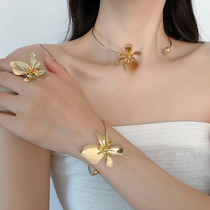 Model wearing a gold floral necklace set including a matching bracelet and ring