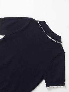 Detail of navy knit top featuring white wavy trim on collar and sleeves close-up
