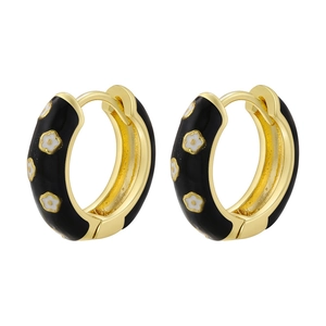 Detailed macro view of gold-plated black enamel hoop earrings with white daisy patterns