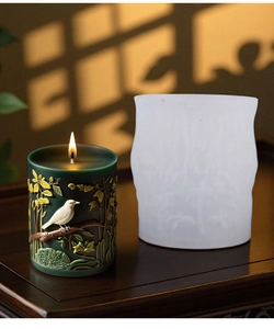 Detailed relief bird and leaf patterns on a cylindrical handmade candle and silicone mold