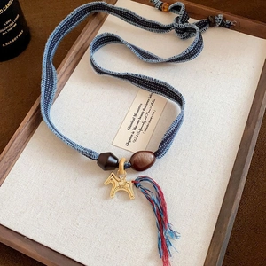 Close-up of golden horse pendant with colorful cotton tassels on vintage necklace