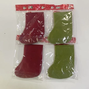 Flat lay detail of four red and green velvet Christmas stockings in plastic packaging
