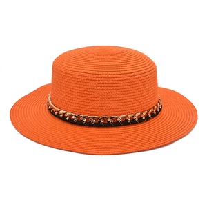 Détail du chapeau de paille orange à bord large avec chaîne dorée et haut plat