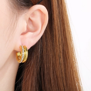 Close-up of gold C-shaped earring with sparkling cubic zirconia on a female model