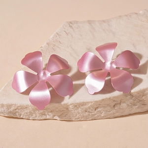 Detail of pink matte metallic flower earrings resting on an ivory textured stone block