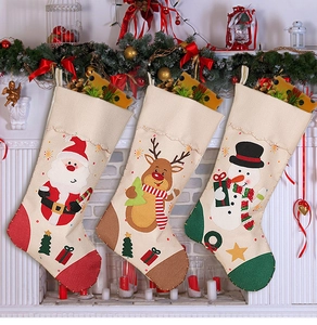 Close-up of three rustic burlap Christmas stockings featuring Santa, reindeer and snowman decals