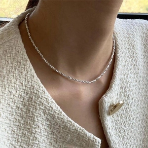 Detail of 925 sterling silver beaded necklace on collarbone with tweed jacket backdrop