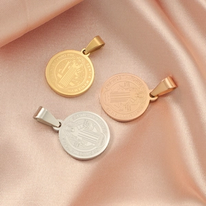 Detailed view of Saint Benedict medals in gold, rose gold and silver on pink silk