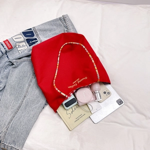 Bolso tote de lona roja con asa de cuentas de colores con tableta y objetos diarios