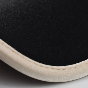 Macro shot of black velvet fabric with fine beige piping and precise stitching detail