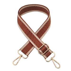 Detail of woven herringbone bag strap in brown and beige with gold metal lobster clasps