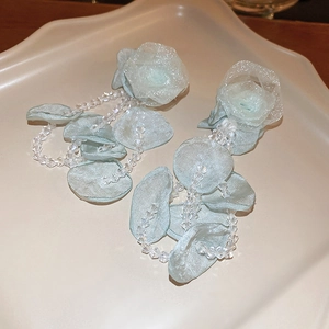 Détail de boucles d'oreilles fleurs en organza vert menthe avec glands en perles fines