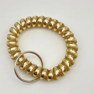 Golden translucent spiral wrist keychain with a silver metal ring on a white backdrop
