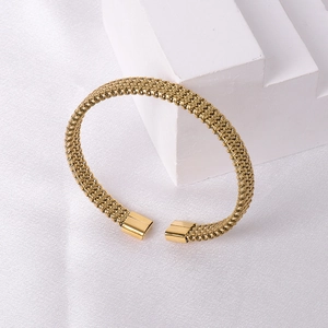 Detailed close-up of golden mesh braided texture on a stainless steel open cuff bracelet