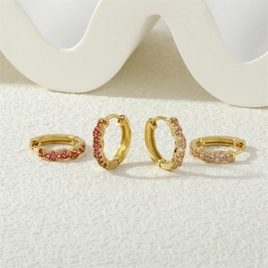Detail of gold huggie earrings with micro-inlaid red and pink round-cut zircons