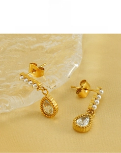 Detailed close-up of gold-plated teardrop earrings with white pearls and sparkling zircons