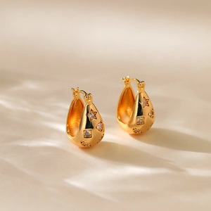 Close-up of gold-plated geometric star earrings with cubic zirconia and hollow design