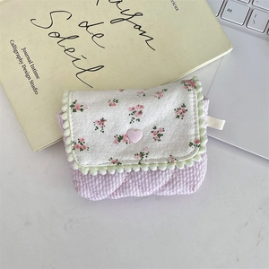 Detail of floral and plaid fabric storage pouch with heart buckle on a desk