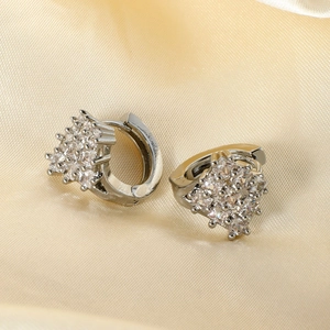 Macro shot of silver hoop earrings with micro-set white zircon on beige satin fabric