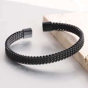 Detail of black woven stainless steel cuff bracelet with textured honeycomb pattern