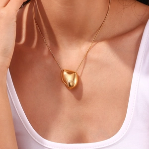 Close-up of a gold stainless steel necklace with an irregular pebble pendant on a model