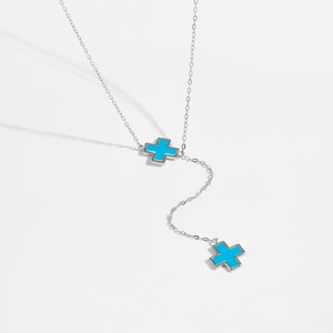 Detailed close-up of a silver Y-necklace with two blue cross pendants on a fine chain