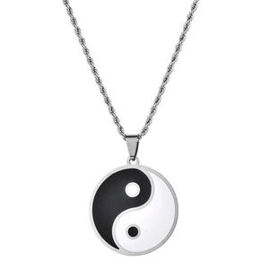Close-up of yin yang pendant with silver twisted chain on white background