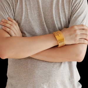 Macro detail of men's wide gold braided wheat chain bracelet with a mirror buckle clasp