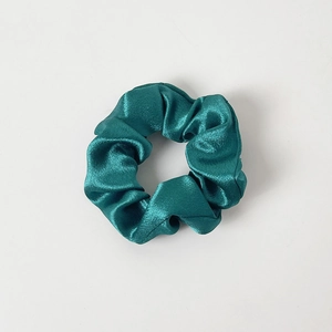 Detailed top view of a dark emerald green silk satin scrunchie with elegant pleats