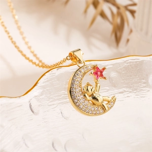 Macro shot of gold moon pendant with bear carving and pink star zircon detail