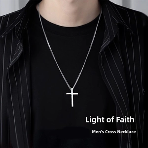 Gros plan d'un collier pendentif croix en acier titane pour homme porté par un mannequin