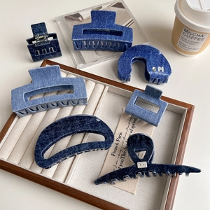 Denim blue acetate hair claws in various geometric shapes on a wooden display tray