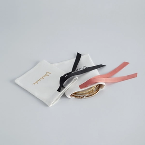 Detailed view of three gold bangle bracelets with crystals and branded drawstring pouches