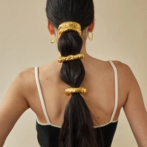 Golden hammer-textured metal ponytail ring and earrings set on model with chic ponytail