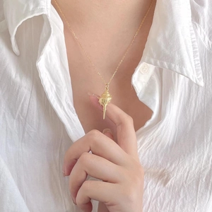 Elegant gold shell pendant necklace for women on white shirt, minimalist coastal jewelry
