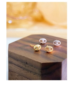 Macro shot of silver and gold pig nose earrings with pave zircons on wood stand