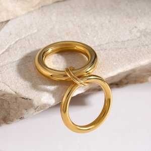Detail of 18k gold-plated interlocking rings on stone surface with polished finish