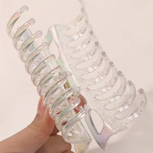 Macro detail of large iridescent hair claw clip showing glossy rainbow finish and metal spring