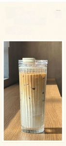Detailed view of a 600mL glass coffee cup with vertical stripes on a wooden desk