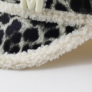 Détail macro du tissu léopard avec bordure en peluche blanche et logo lettre M en 3D