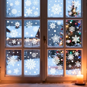 White snowflake static window decals on a glass window with cozy winter scenery background