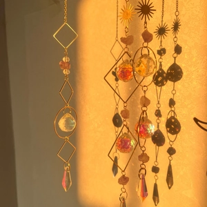 Detailed view of crystal sun catcher with gold geometric frames casting prism reflections