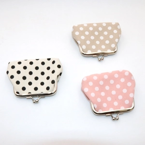 Detailed view of polka dot canvas coin purses with metal clasps in khaki and pink