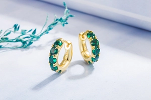Macro shot of S925 sterling silver emerald earrings with gold plating and green zircon