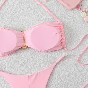 Detailed view of pink bikini top with golden ring connector on white faux fur